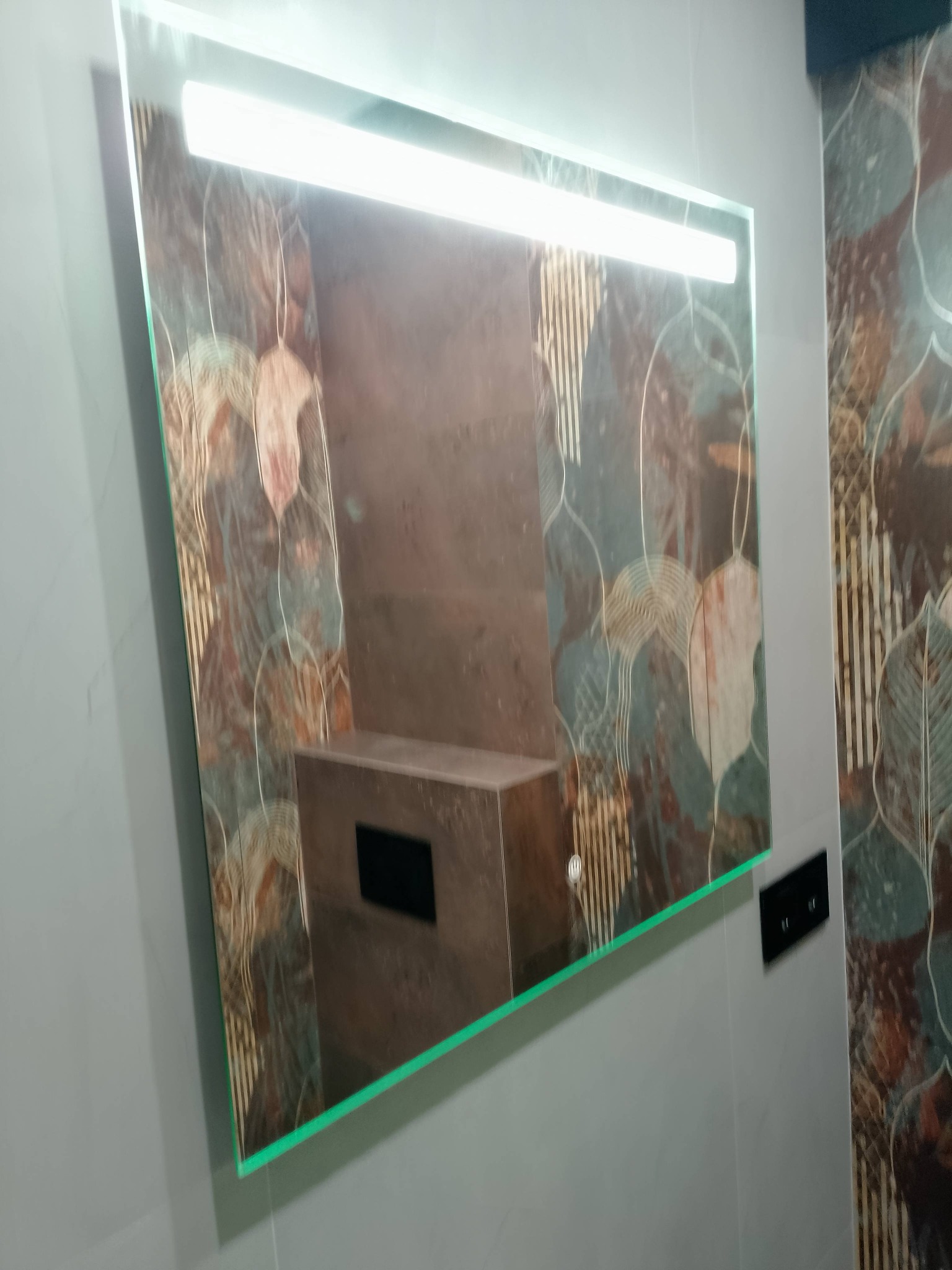 Podświetlane lustro w łazience z wzorzystymi płytkami. Nowoczesny design z zieloną obwódką i dotykowym włącznikiem. Element wykończenia wnętrza łazienki.