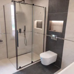 Nowoczesna łazienka w Wojska z kabiną prysznicową typu walk-in z czarnymi profilami, podwieszaną toaletą i wnękami ściennymi z podświetleniem LED.