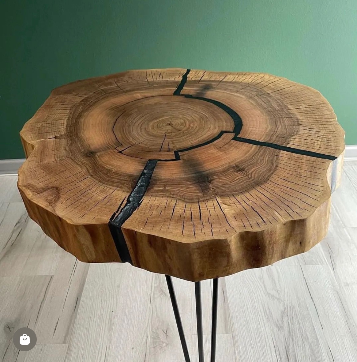 Stolik kawowy z blatem z plastra drewna z żywicą epoksydową, widoczne słoje i pęknięcia wypełnione czarną żywicą, na metalowych nóżkach.