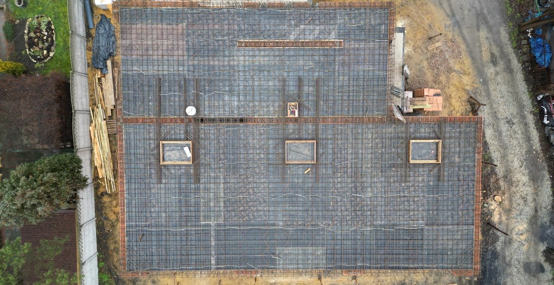 Zbrojenie fundamentów domu jednorodzinnego z widocznymi otworami na instalacje, ujęcie z drona.