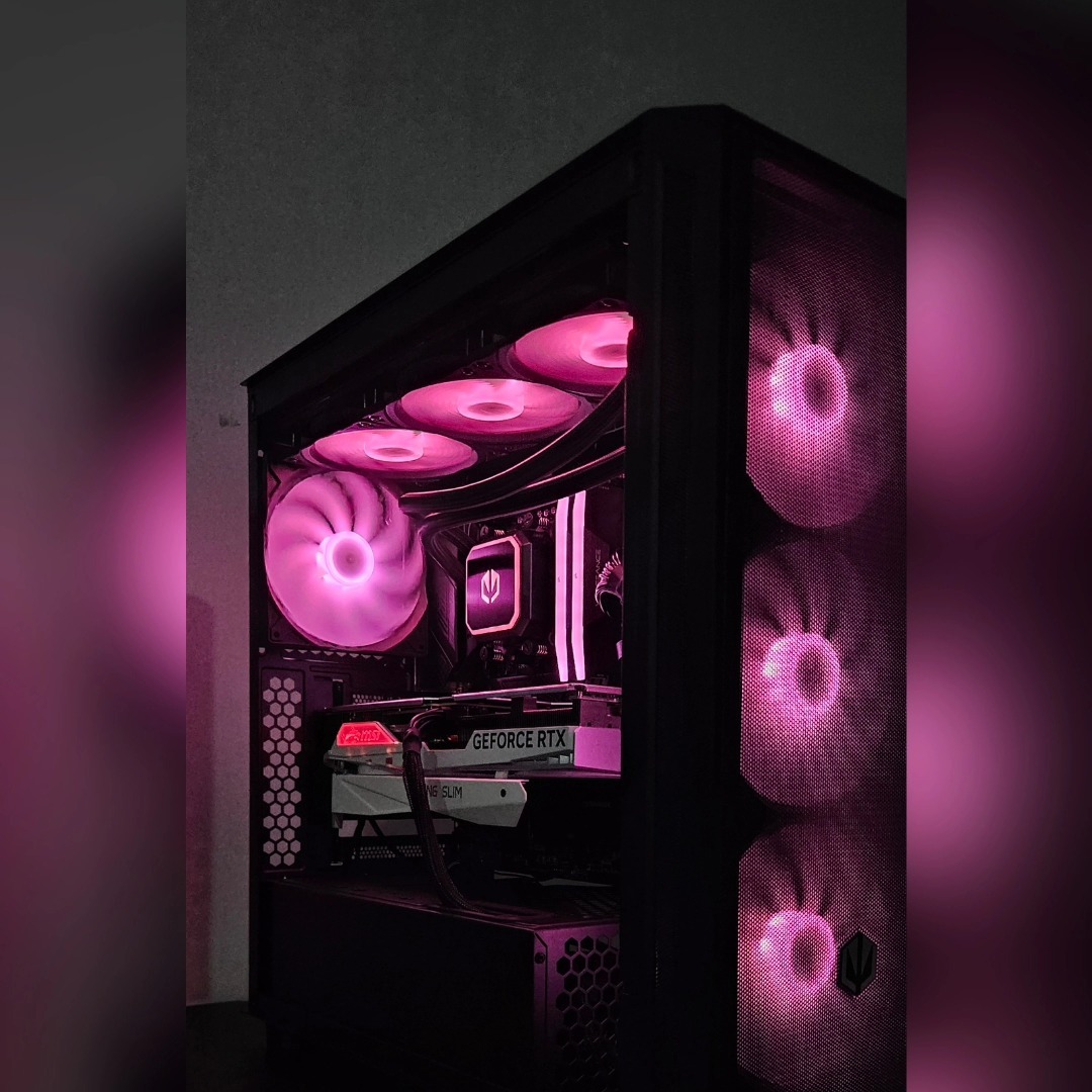 Otwarta obudowa komputera stacjonarnego z widocznymi podzespołami podświetlonymi na różowo, w tym wentylatory, karta graficzna GeForce RTX i chłodzenie wodne.