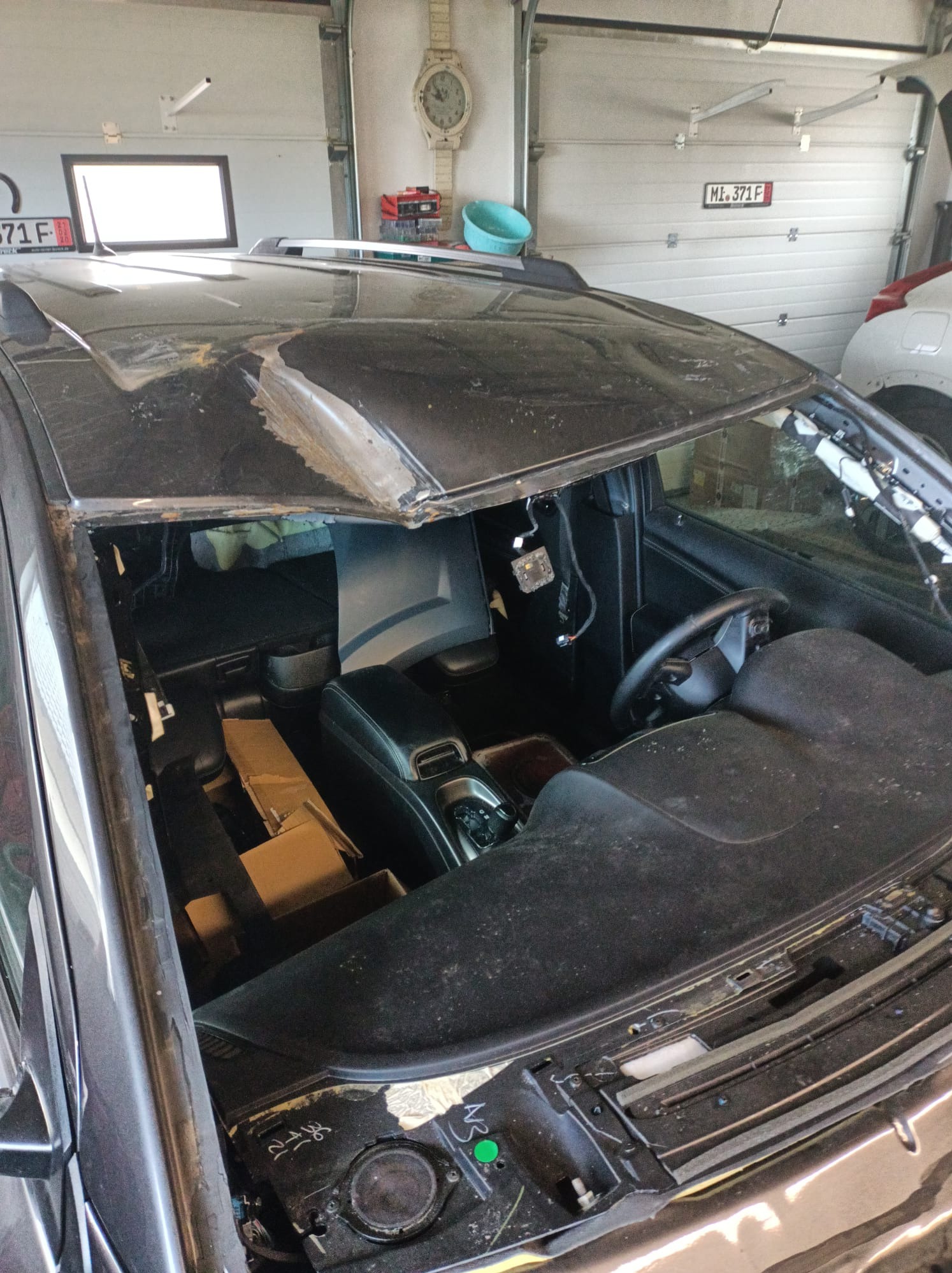 Uszkodzony dach i wnętrze samochodu po wypadku w warsztacie w Bytowie, widoczne zdemontowane elementy i uszkodzenia karoserii.