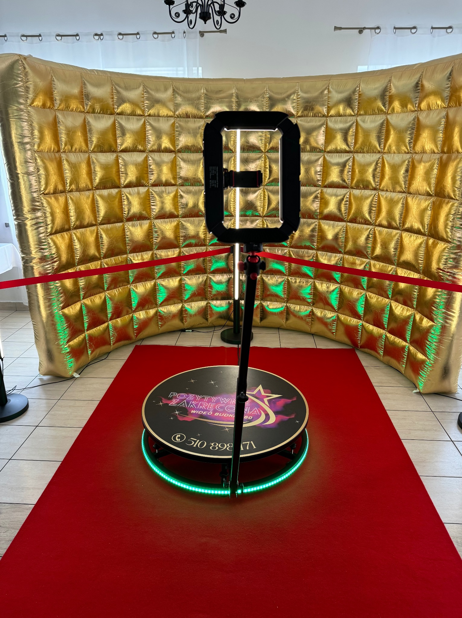 Rotująca platforma z oświetleniem LED i tłem z pikowanych, złotych paneli, otoczona czerwoną taśmą.