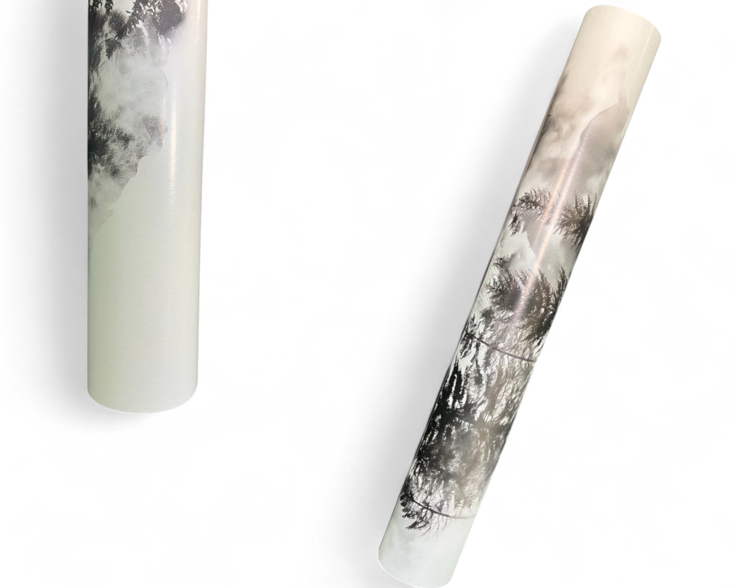 Dwa zwinięte plakaty z motywem górskiego krajobrazu w odcieniach szarości, leżące na białym tle.