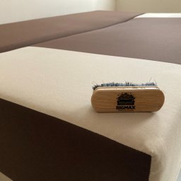 Władysław Kudriaszow BigMax Clean - Szczotka do czyszczenia tapicerki z logo firmy BIGMAX leżąca na dwukolorowej kanapie w odcieniach beżu i brązu.