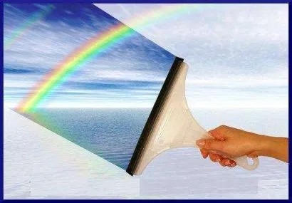 Dłoń trzymająca ściągaczkę do okien, odsłaniającą widok na morze i tęczę przez czystą szybę.