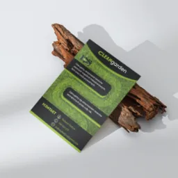 Ulotka reklamowa firmy CleanGarden, specjalizującej się w utrzymaniu terenów zielonych, leżąca na kawałku kory drzewnej, na jasnym tle. Ulotka w kolorach zieleni i czerni, z widocznym logo i danymi...