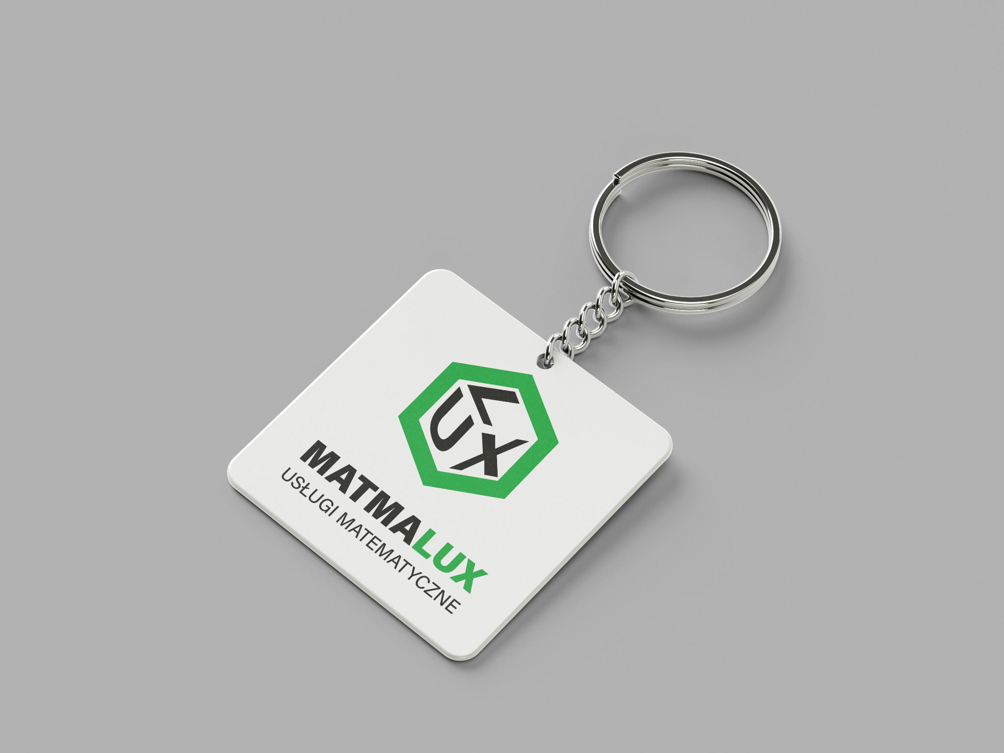 Biały, kwadratowy brelok z logo 'MATMALUX Usługi Matematyczne' na szarym tle, widoczne metalowe kółko i łańcuszek.