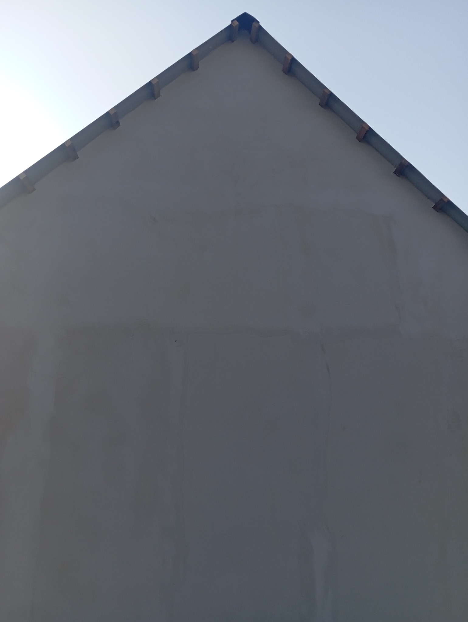 Szczyt ściany budynku z widocznymi śladami po wcześniejszych pracach, przygotowany do dalszych etapów wykończeniowych.