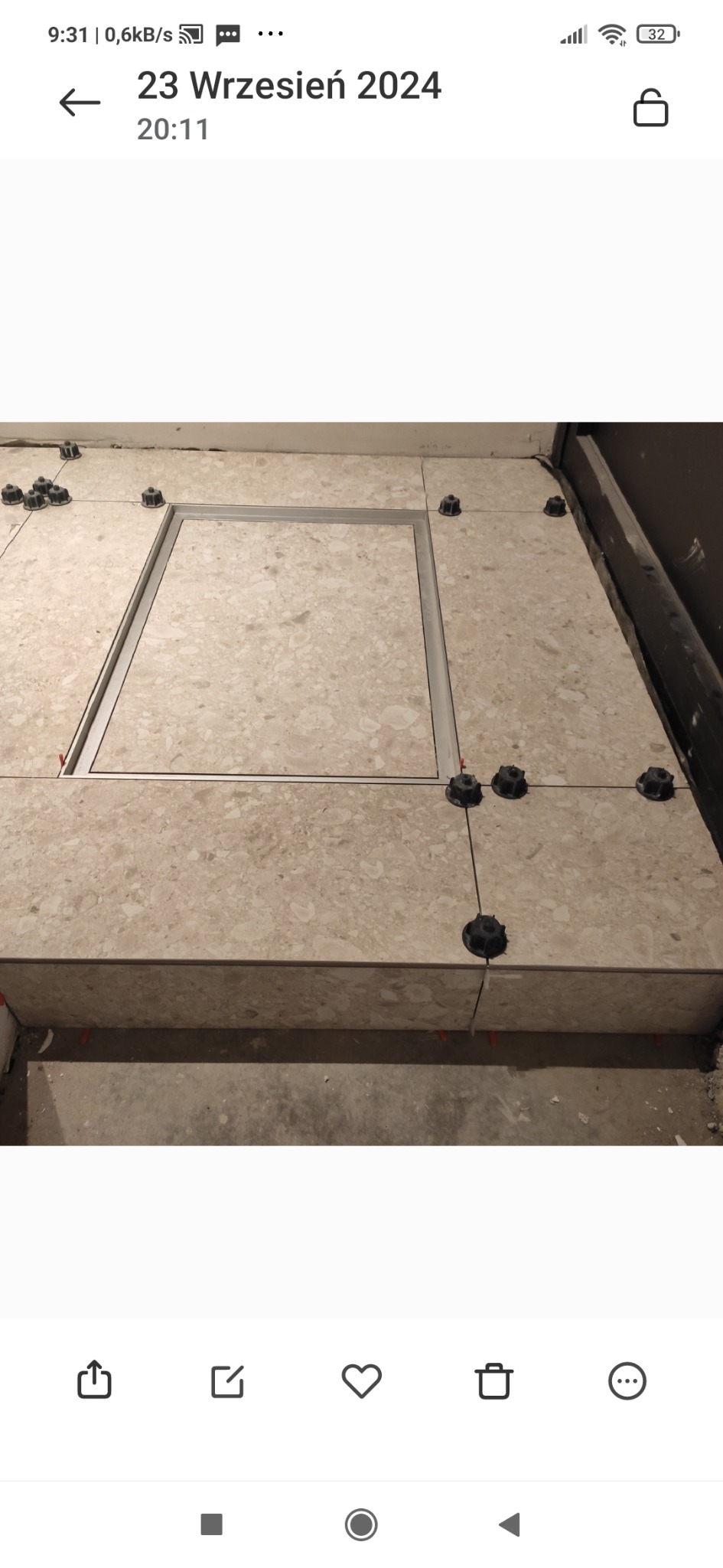 Układanie płytek podłogowych z beżowego marmuru z widoczną ramą inspekcyjną i systemem poziomowania płytek.