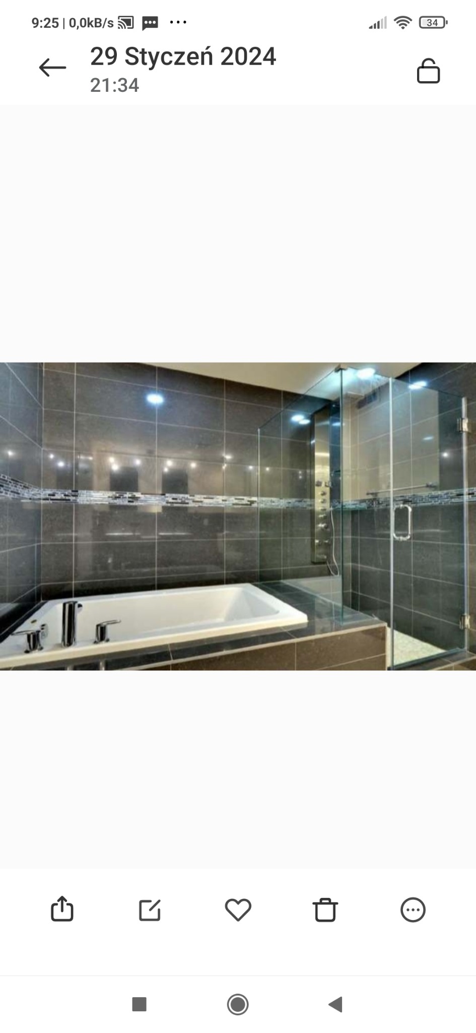 Nowoczesna łazienka z ciemnymi płytkami, białą wanną i przeszkloną kabiną prysznicową z deszczownicą, wykończona mozaiką.