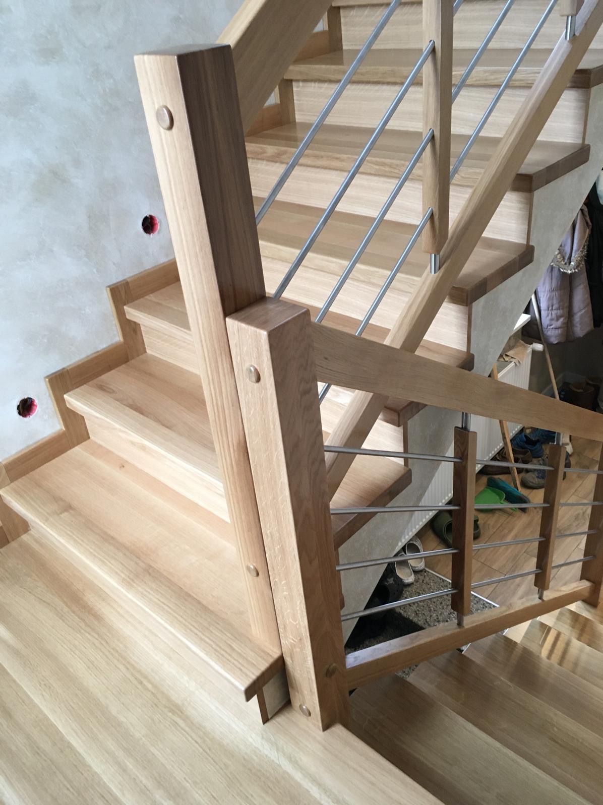 Jasne schody z drewna z metalową balustradą, widok z góry, detale łączeń elementów, minimalistyczny design, surowe ściany w tle, naturalne światło.