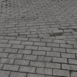 PPHU PIT-GRAN - Szara kostka brukowa ułożona na ulicy z widocznym przejściem dla pieszych i studzienką kanalizacyjną, lekko wilgotna powierzchnia.