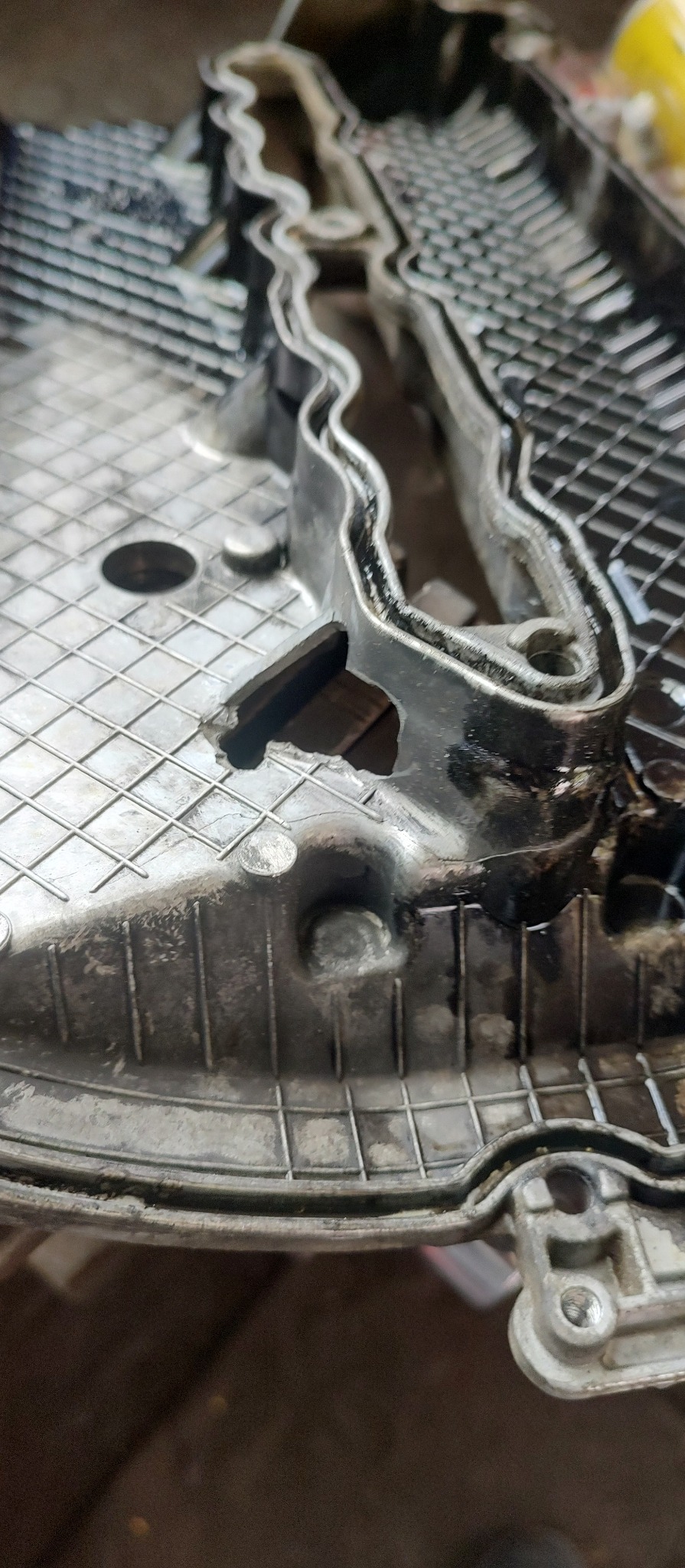 Szczegółowe zbliżenie na odlew metalowy z widoczną strukturą kratową i śladami oleju, ukazujące precyzję wykonania i potencjalne uszkodzenia w materiale.