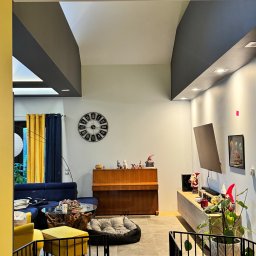 FlexiWorks-Przemysław Wolnik - Nowoczesny salon z szarą podsufitką, pianinem pod ścianą i różnorodnymi elementami dekoracyjnymi, oddzielony barierką zabezpieczającą.