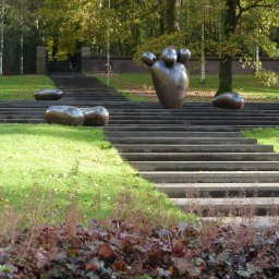 BIURO ARCHITEKTURY KRAJOBRAZU Agata Michalska - Schody z rzeźbami w parku, widok na wzniesienie z zielonym trawnikiem i drzewami w tle.