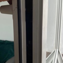 Tymur Klochko - Uszczelka okienna dociskana palcem do ramy, widoczne ślady zabrudzeń na białej ramie okiennej.