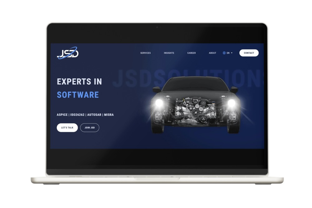Ekran laptopa wyświetlający stronę internetową firmy JSDSolution z hasłem 'Experts in Software' i wizualizacją silnika samochodowego na ciemnoniebieskim tle.