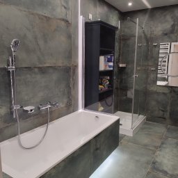 Dom i k sp. z oo - Nowoczesna łazienka z wanną, kabiną prysznicową i ciemnozielonymi płytkami imitującymi kamień, podświetlenie LED pod wanną, szafka z półkami na akcesoria łazienkowe.