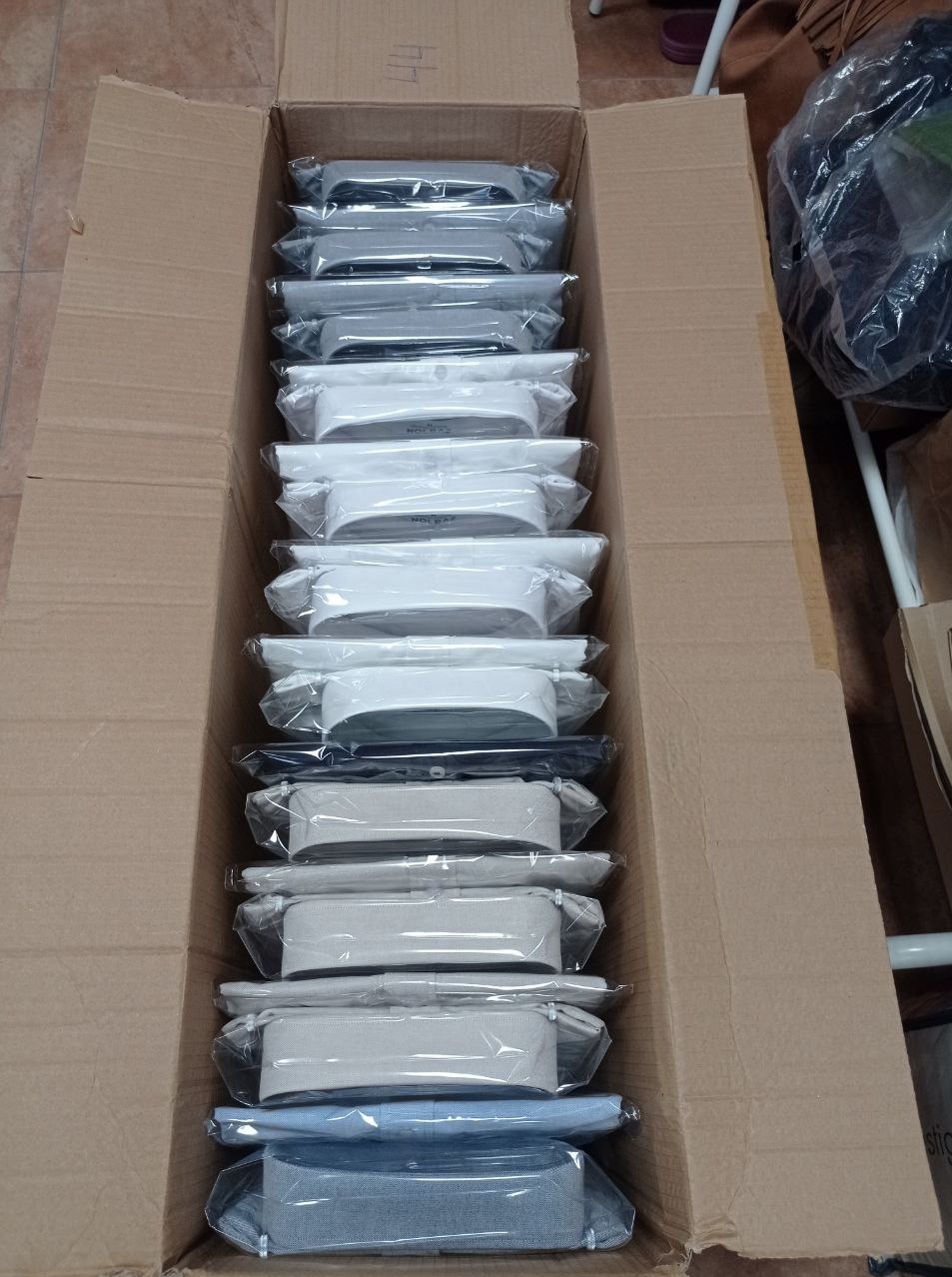 Stos koszul męskich, zapakowanych pojedynczo w folię, ułożonych w kartonowym pudle, gotowych do wysyłki.