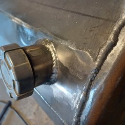 Przedsiębiorstwo Techniczne MTC Wiktor Suska - Zbliżenie na spawaną metalową konstrukcję z nakrętką, ukazujące precyzyjne spoiny i surowy wygląd metalu.