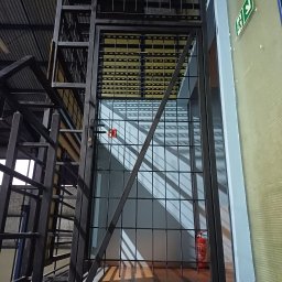 Przedsiębiorstwo Techniczne MTC Wiktor Suska - Metalowa konstrukcja schodów z zabezpieczeniem w postaci kraty, widoczny znak ewakuacyjny i gaśnica w tle.