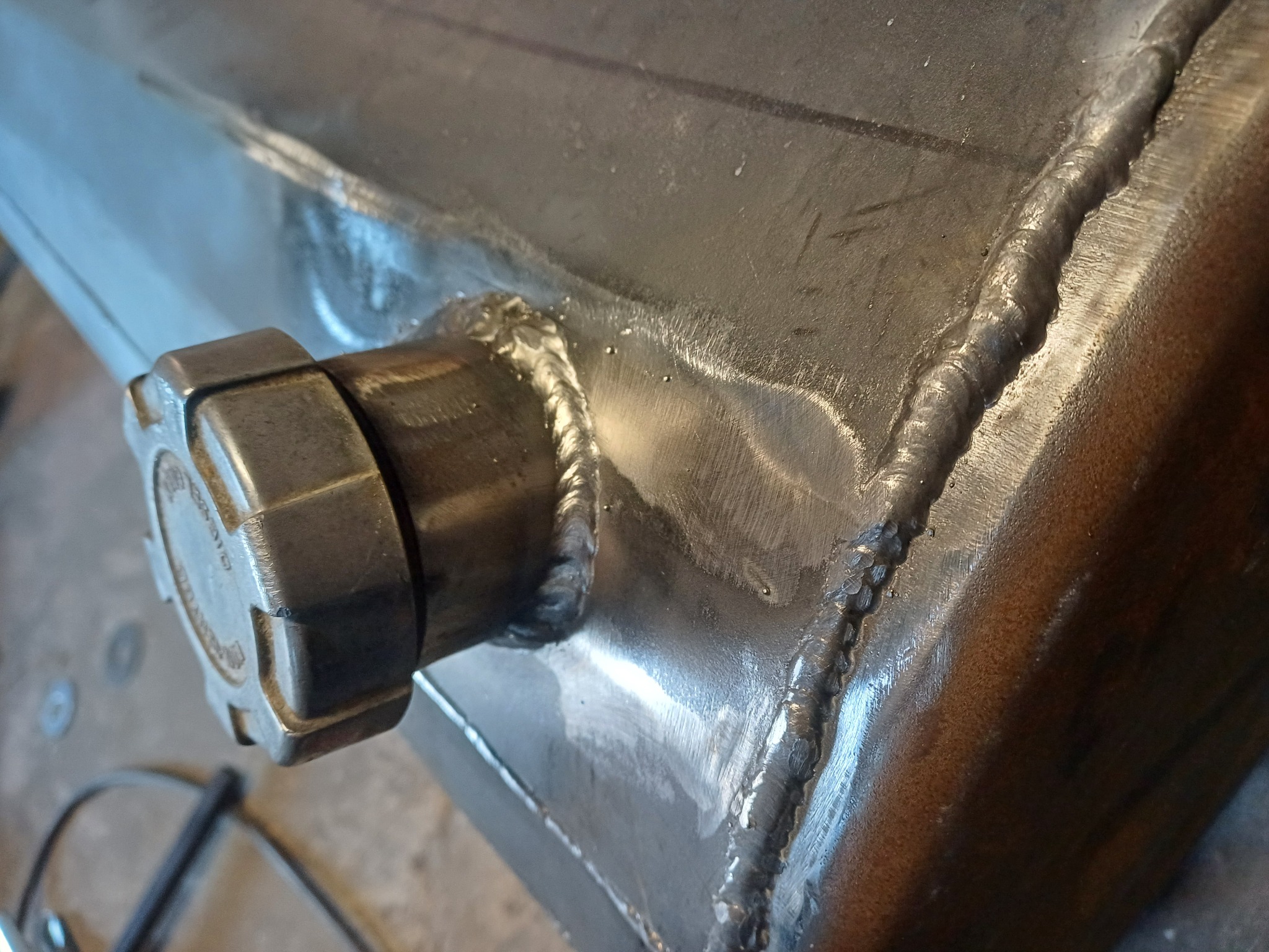 Zbliżenie na spawaną metalową konstrukcję z nakrętką, ukazujące precyzyjne spoiny i surowy wygląd metalu.