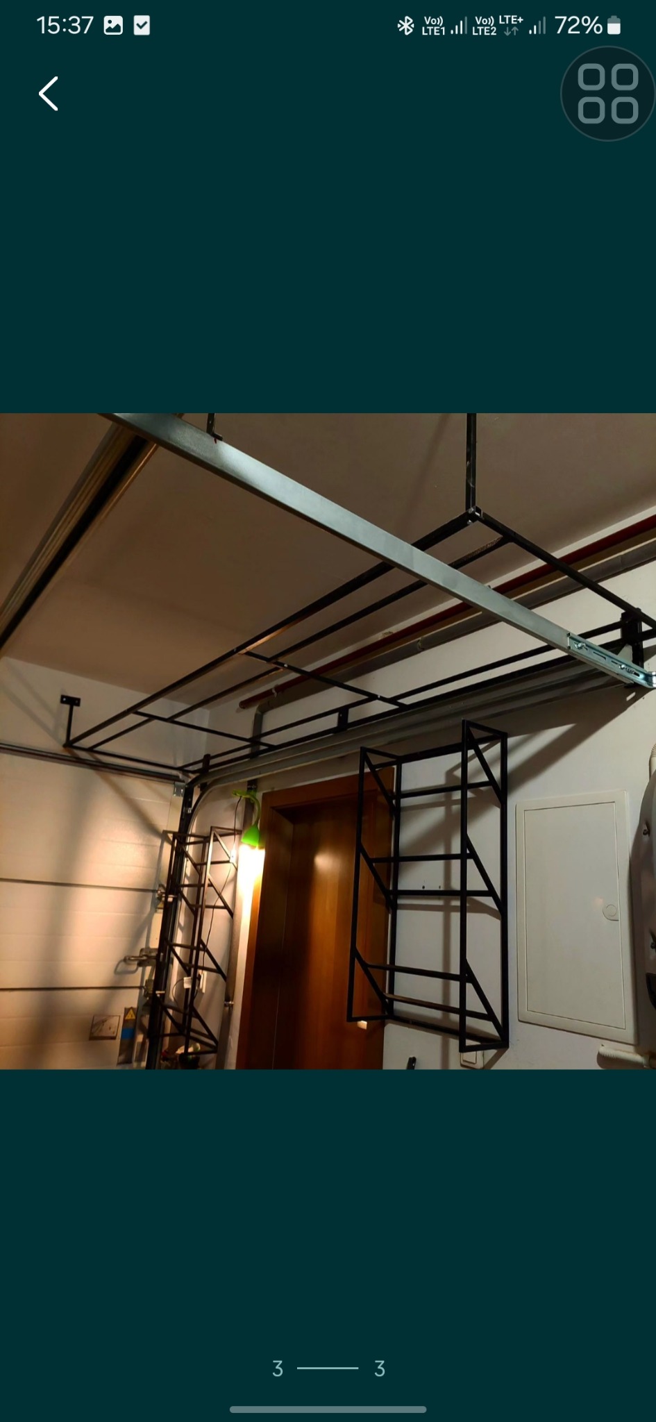 Metalowa konstrukcja sufitowa z elementami drabiny przymocowanymi do ściany, widoczne rury i instalacje pod sufitem, oświetlenie z zieloną lampką.