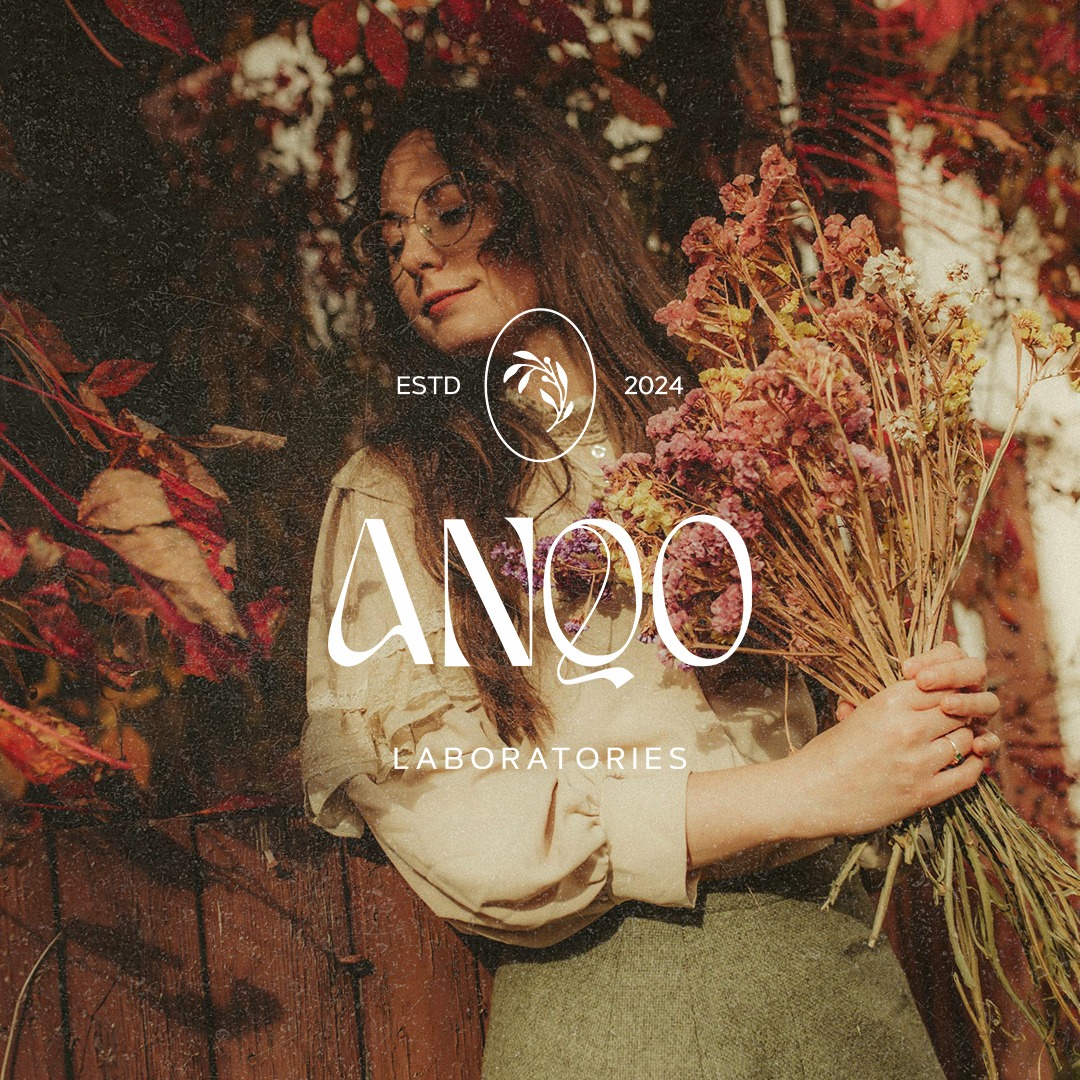 Kobieta w okularach trzyma bukiet suszonych kwiatów na tle drewna i jesiennych liści, z nałożonym logo i nazwą firmy ANQQ Laboratories, data ESTD 2024.