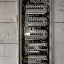 Kamil Sułkowski - Rozdzielnia elektryczna z zainstalowanymi zabezpieczeniami nadprądowymi i przeciwprzepięciowymi marki Eaton, widoczna na tle ściany z betonu komórkowego z widocznymi śladami ołówka.