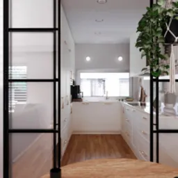 Wnętrze kuchni w stylu skandynawskim z białymi szafkami, drewnianą podłogą i czarnymi, przeszklonymi drzwiami przesuwnymi; na pierwszym planie fragment okrągłego, drewnianego stołu z logo projektanta.