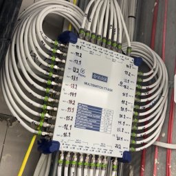 VoltSky Szymon Zaremba - Multiswitch Telmor TT-9/24 z podłączonymi kablami koncentrycznymi, widoczne oznaczenia wyjść i parametry techniczne na obudowie, instalacja w surowym stanie, kable oznaczone numerami VL1, VL2.