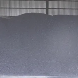 Duża pryzma antracytu pod zadaszeniem magazynu, widoczne metalowe podpory konstrukcji.