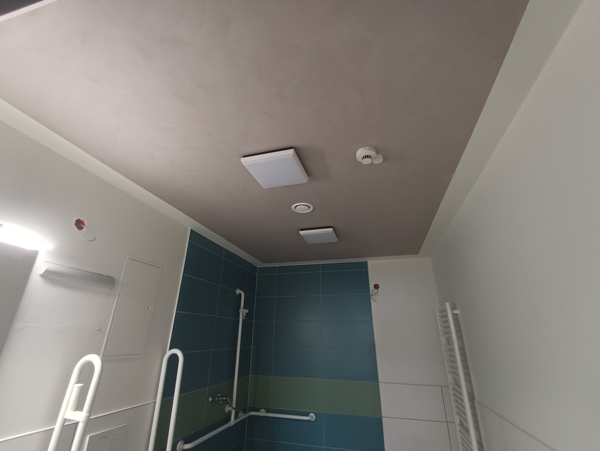 Wykończona łazienka z dwukolorowym sufitem (szary środek i białe obramowanie), oświetleniem LED i czujnikiem dymu.