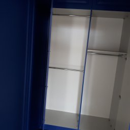 WIEWIÓR SPÓŁKA Z OGRANICZONĄ ODPOWIEDZIALNOŚCIĄ - Otwarty, niebieski szafa z dwiema półkami na ubrania i białym wnętrzem, widok z dołu.