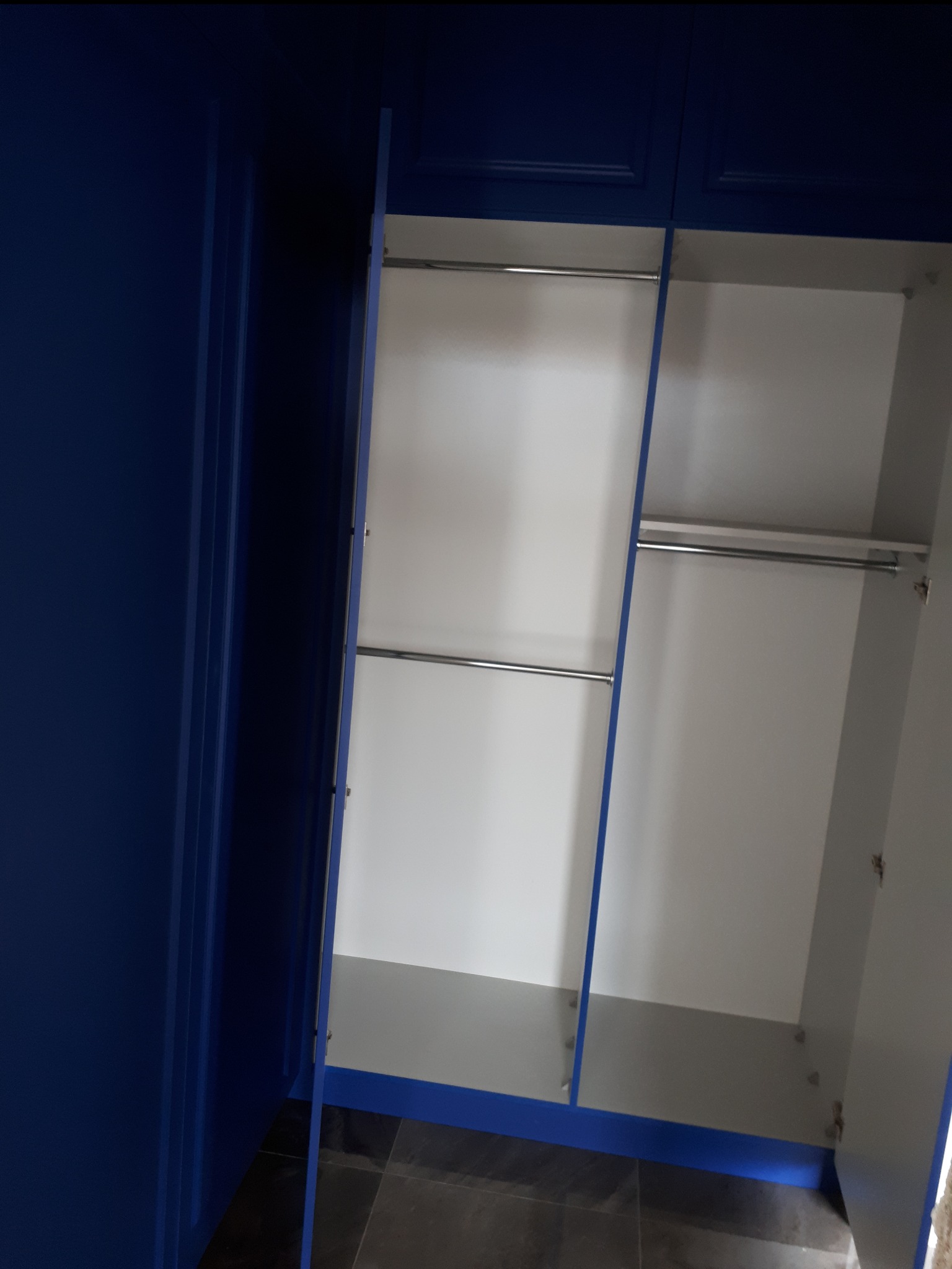 Otwarty, niebieski szafa z dwiema półkami na ubrania i białym wnętrzem, widok z dołu.