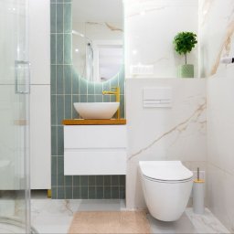 Studio Projektowe Decorfun - Nowoczesna łazienka z umywalką nablatową, złotą armaturą i zielonymi płytkami. Minimalistyczny design, białe marmurowe płytki i oświetlenie LED.