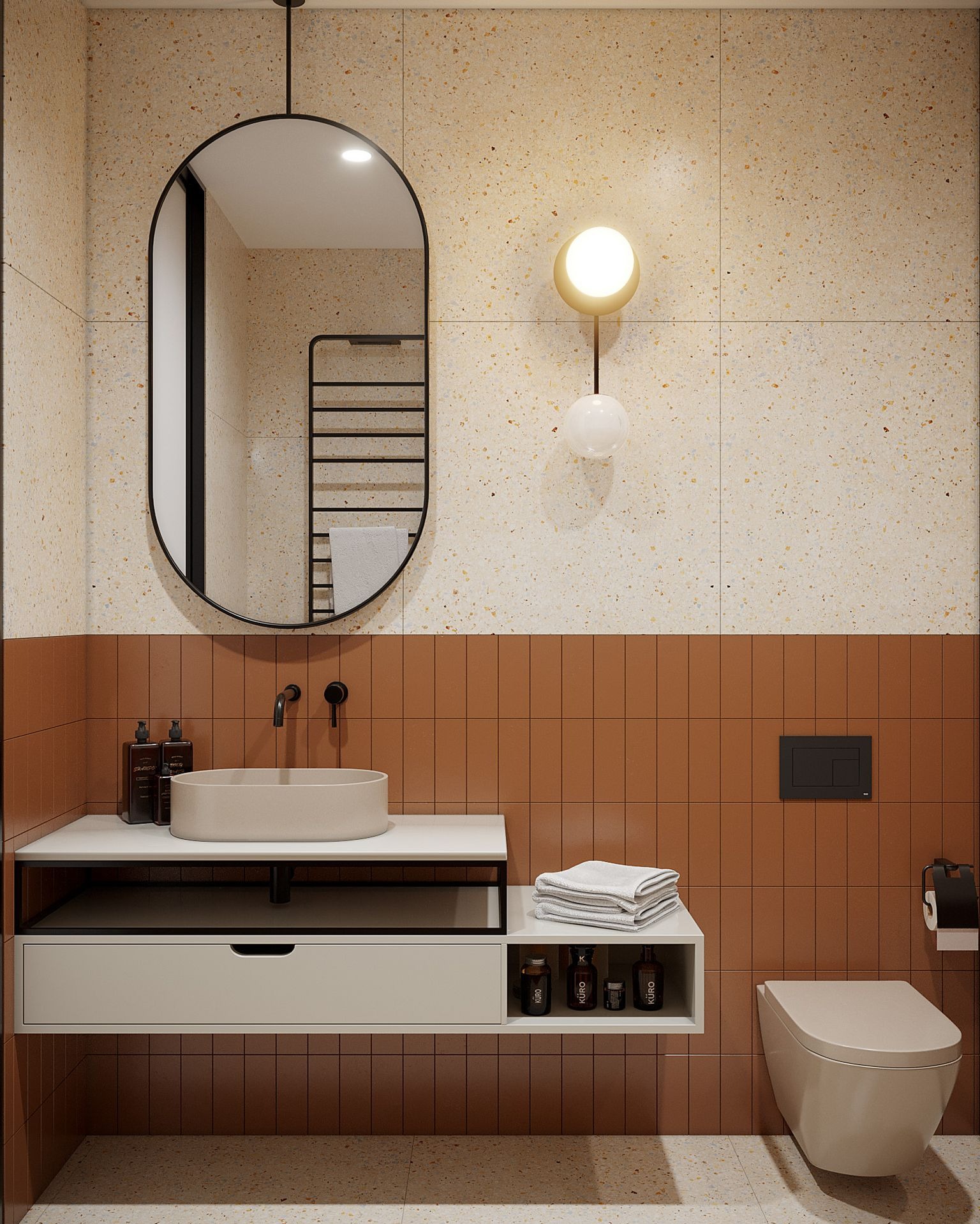 Nowoczesna łazienka z umywalką nablatową, owalnym lustrem z czarną ramą, brązowymi płytkami i beżowymi płytkami lastryko na ścianach oraz wiszącą toaletą i subtelnym oświetleniem.