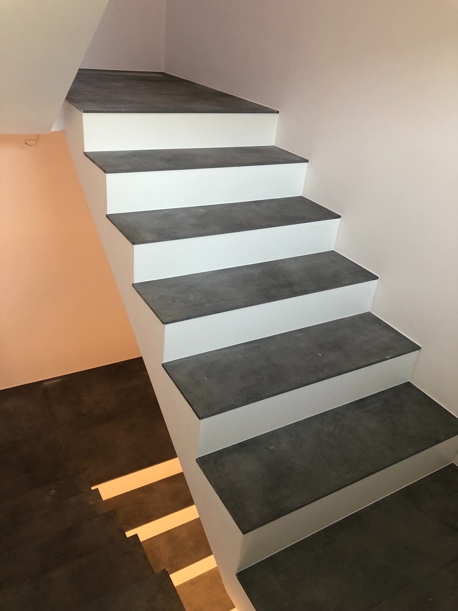 Nowoczesne schody z szarymi stopniami i białymi podstopnicami, widok z góry, minimalistyczny design.