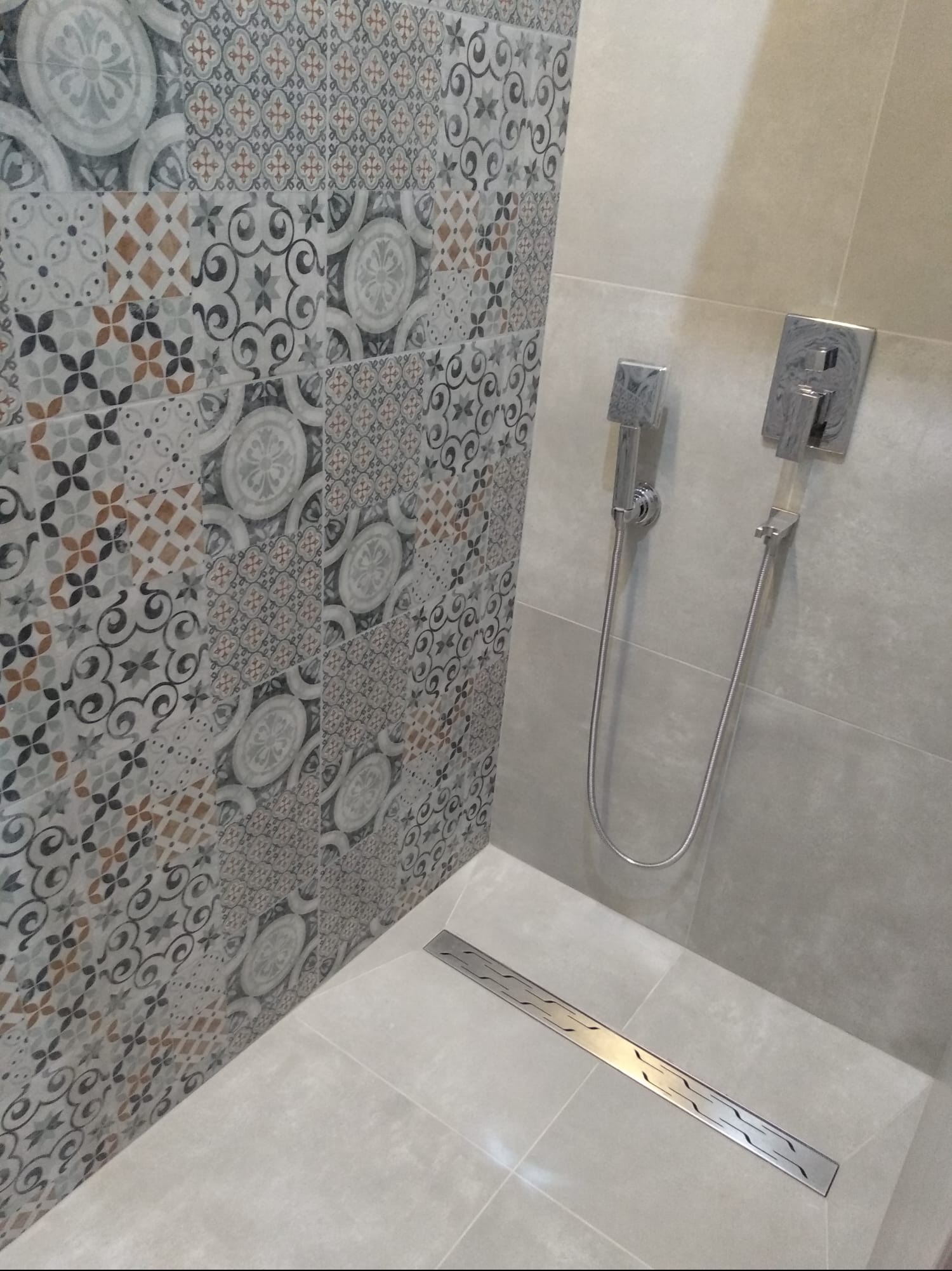 Wzorzyste płytki ścienne i natrysk w nowoczesnej łazience we Wrocławiu. Uwagę przykuwa liniowy odpływ podłogowy i minimalistyczna armatura.