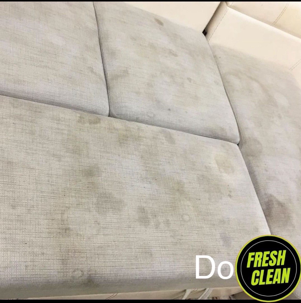 Beżowa sofa z widocznymi, ciemnymi plamami na siedzisku przed czyszczeniem, z naklejoną grafiką 'Do Fresh Clean'.
