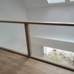 Drew Max - Szklana balustrada z drewnianą ramą na antresoli, widok na zewnątrz, jasne drewno, minimalistyczny design, widoczne notatki na szkle.