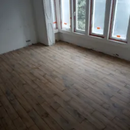 Ułożone panele podłogowe w jasnym pokoju z trzema oknami zabezpieczonymi folią malarską, widoczne ślady prac wykończeniowych na ścianach.