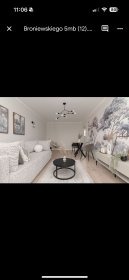 Jasne wnętrze salonu z sofą, okrągłym stolikiem kawowym i fototapetą z motywem drzew. Nowoczesne oświetlenie i minimalistyczny design.