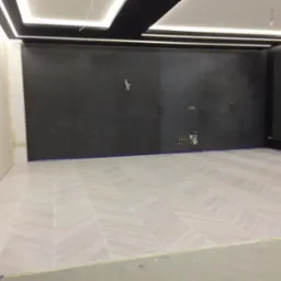 Jasna podłoga ułożona w jodełkę w pokoju z czarną ścianą i nowoczesnym oświetleniem sufitowym, widoczne przygotowania do dalszych prac wykończeniowych.