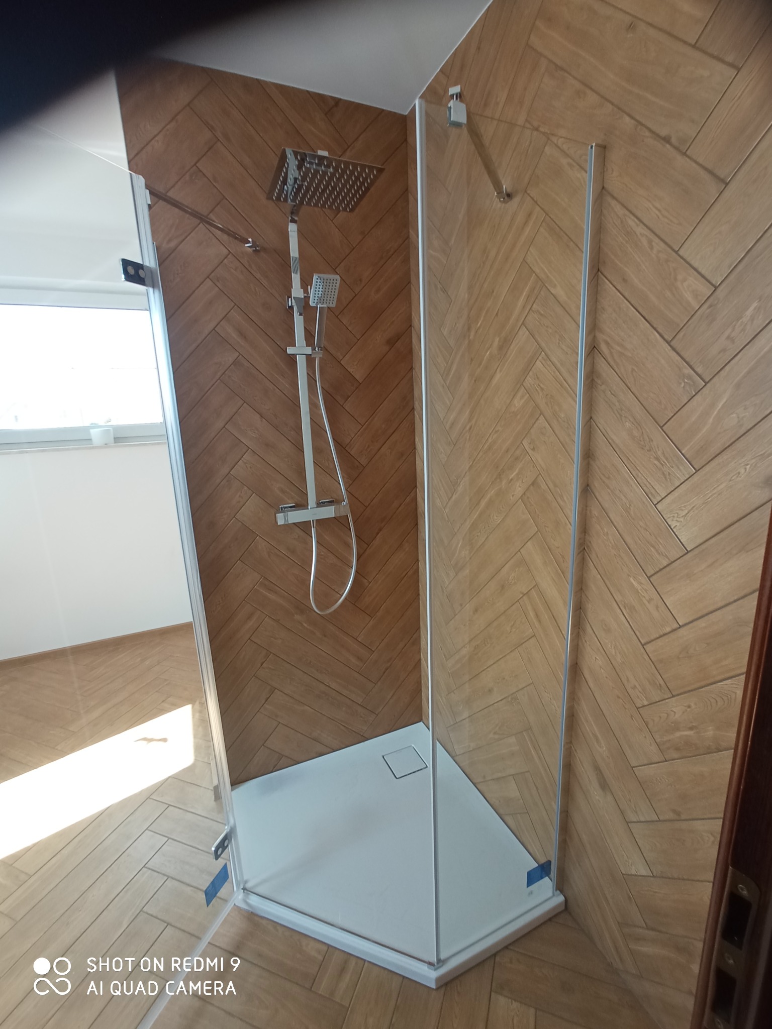 Kabina prysznicowa z deszczownicą i panelami ściennymi ułożonymi w jodełkę, widok z otwartymi drzwiami kabiny