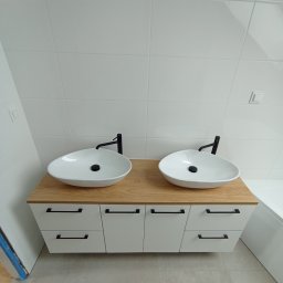 STYL DREAM HOME SPÓŁKA Z OGRANICZONĄ ODPOWIEDZIALNOŚCIĄ - Nowoczesna łazienka z dwiema owalnymi umywalkami nablatowymi, czarne baterie, szafka z jasnego drewna z białymi frontami i czarnymi uchwytami, białe płytki na ścianach.