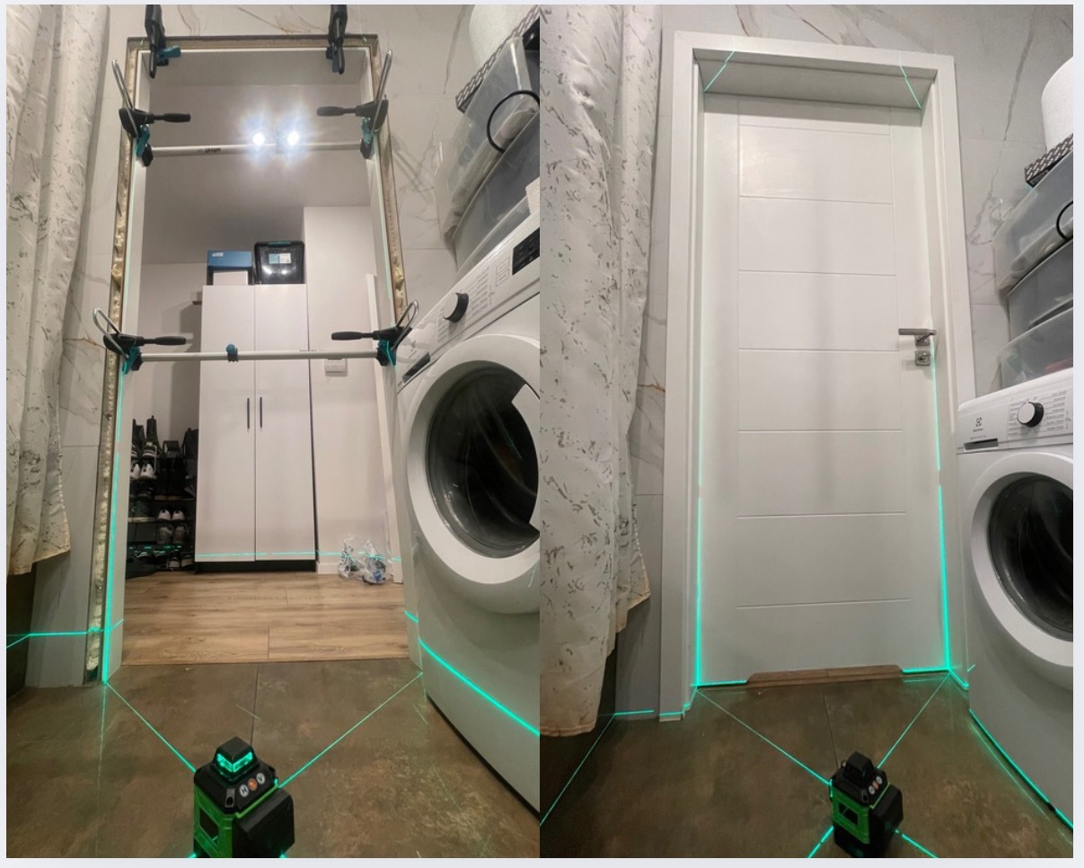 Montaż białych drzwi wewnętrznych w łazience, z użyciem poziomicy laserowej i rozpór, widok na białą pralkę i szafkę w tle.