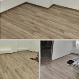 Ułożone panele podłogowe w jasnym odcieniu drewna, widoczne listwy przypodłogowe, w tle fragment pomieszczenia w trakcie remontu z widocznymi elementami konstrukcyjnymi.