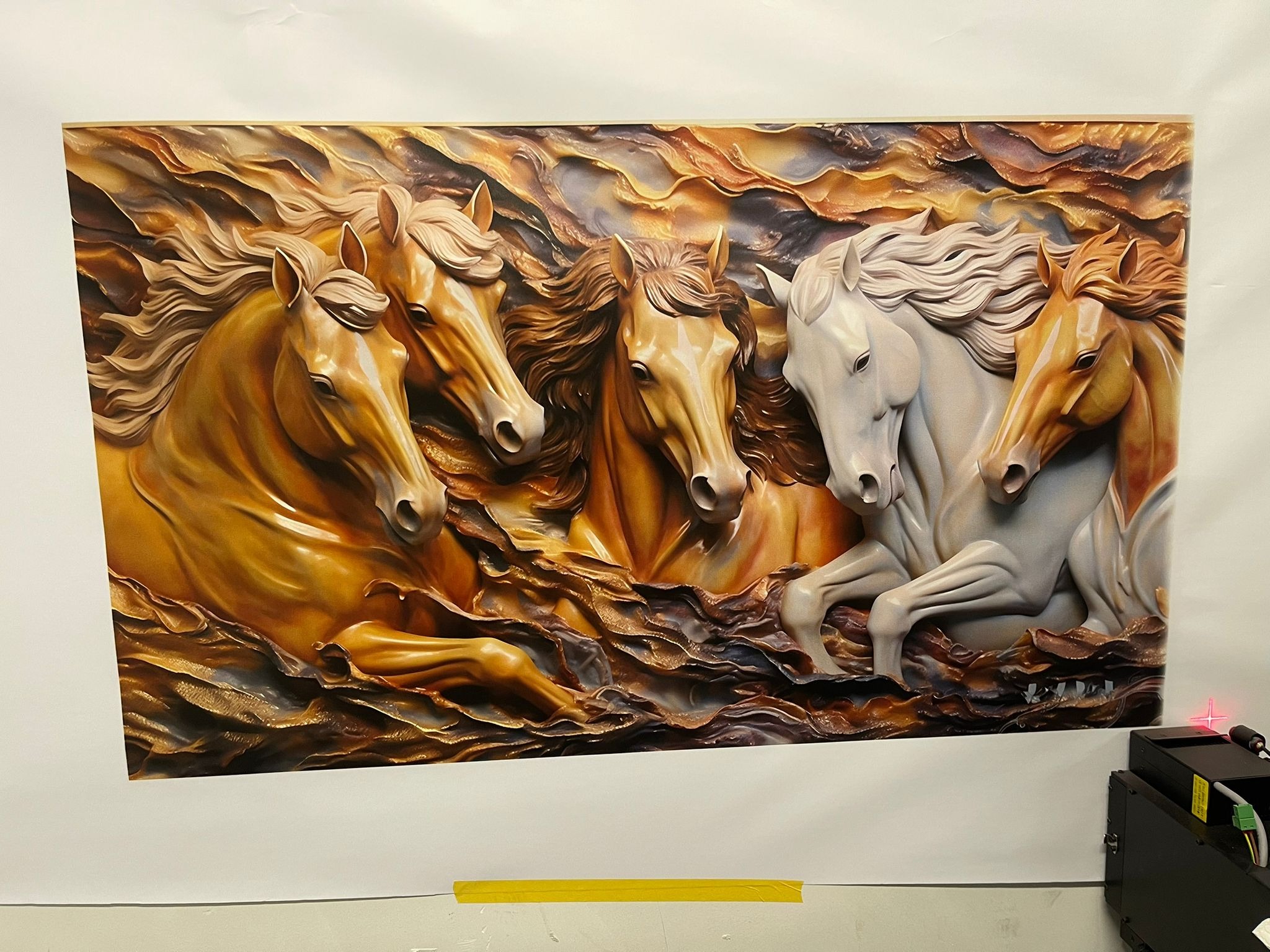 Relief ścienny przedstawiający galopujące konie w odcieniach złota i bieli, z wyraźną fakturą i trójwymiarowym efektem, zawieszony na białej ścianie.